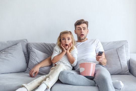 frightened father and daughter watching scarry movie at home