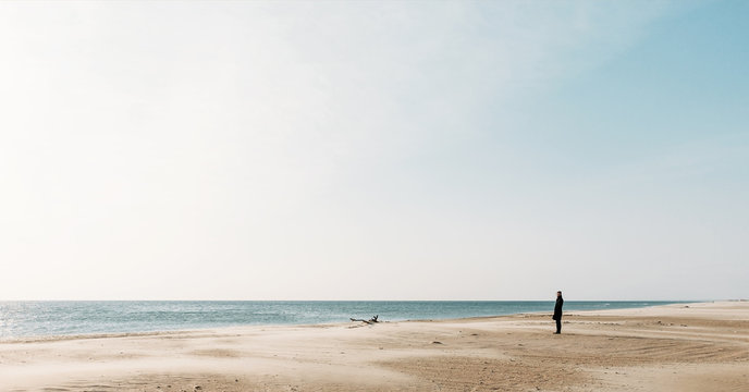 Woman walking on sandy coast.