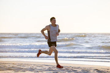 athletic fit and strong runner man training on Summer sunset beach in sea shore running and fitness workout in sport and healthy lifestyle