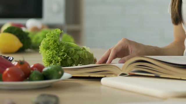Woman reading old grannys recipes book at home exquisite dinner, ingredients