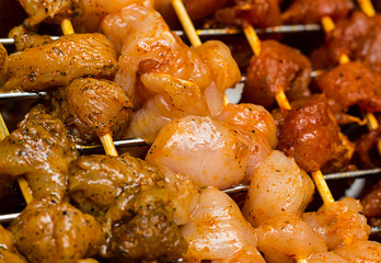 Mix pork chicken with hot spices on skewers on grill lattice metal background close-up