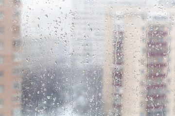 drops of melting snow on window glass in winter