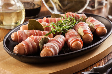 Raw mini sausages wrapped in smoked bacon