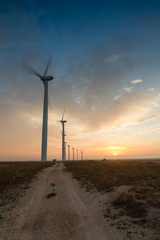 Obraz premium Wind turbines against red, blue and orange sunrise