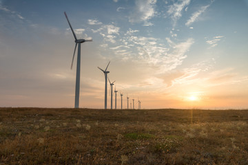 Obraz premium Wind turbines against red, blue and orange sunrise