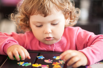 Adorable happy little child playing with puzzle.