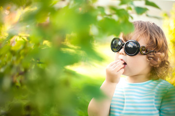 Cute toddler girl eats honeysuckle outdoors.