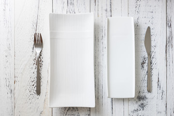 White rectangular Plates with fork and knife on white wooden background