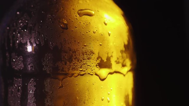 Close-up of a glass bottle with drops of condensed water. Cold drink concept. On a black background