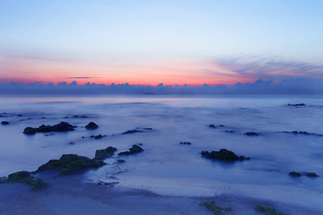 Sunrise over the tropical seacoast beach. The wave of seawater up the beach and waves slowly splashing on the sand.