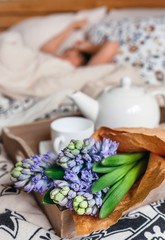 Fototapeta na wymiar Bouquet hyacinth flowers and teapot with fresh tea are on bed for sleeping person