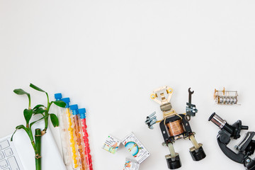 STEM education. Mock up. White background, free space for text. Metal robot made by hands in a class in chemistry and robotics. Background. Free bots. Tubes, tree and microscope and laptop.