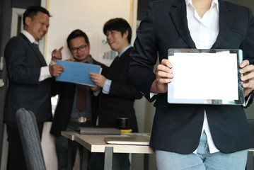 businesswoman hold tablet at workplace. young woman shows information in touchpad at office. freelancer present data in business meeting