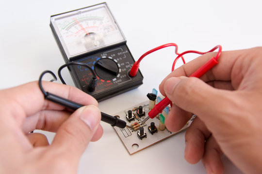 Technician hand with multimeter probes repairing circuit board