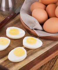 Sliced hard boiled eggs with basket of brown eggs in background