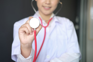 female doctor showing stethoscope for checkup at clinic. physician or medical practitioner holding stethoscope to auscultate breath in medical visit