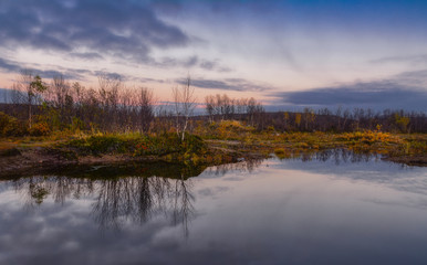 Beautiful autumn sunset on the lake. Reflection of trees in clean calm wat