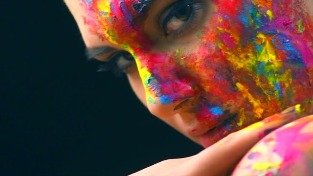 Beauty model girl with colorful paint on her face. Multicolor creative make-up. 4K UHD video footage. 3840X2160