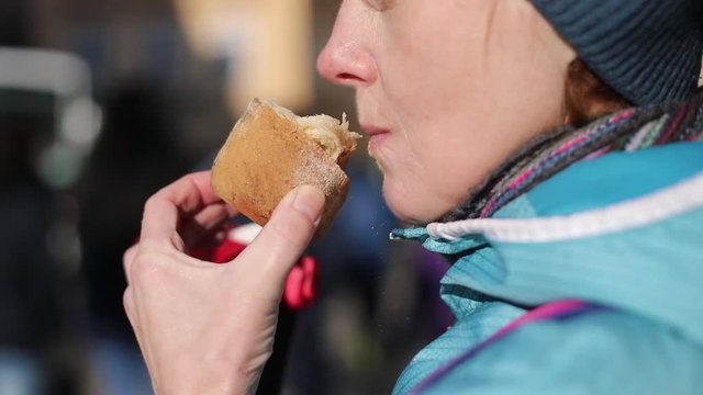 A woman with an appetite eats a traditional sweet biscuit Trdelnik in Prague during Christmas time