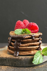Chocolate pancakes with raspberry on a dark background.