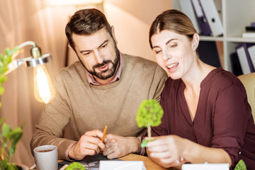 Collective thoughts. Creative architectures sitting together and expressing positivity while looking at model of tree