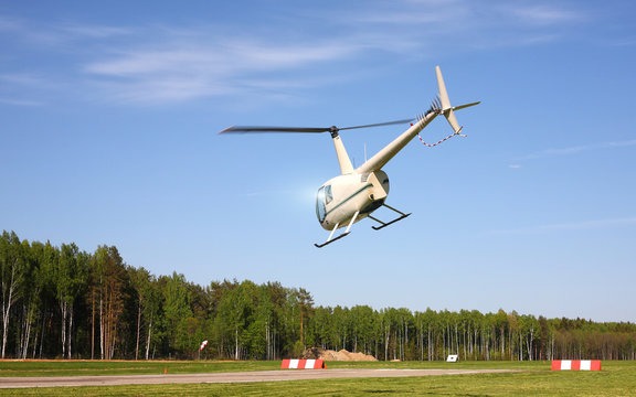 The aircraft - White helicopter makes flight at low height.