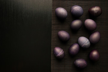 Easter concept painted eggs on black background and red for holiday with place for text dark egg