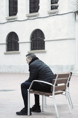 sad man sitting in a bench in the street