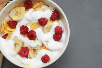 Breakfast with Cereals and Fruits. Banana, Raspberries. Gray Board with Copy Paste.