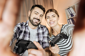 Keep smiling. Cheerful couple expressing positivity and touching camera while looking forward