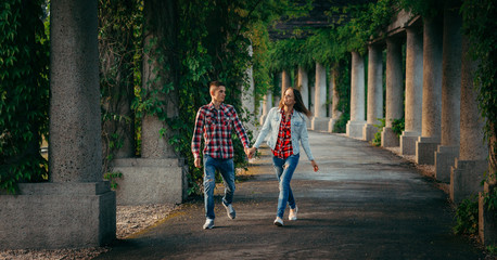 Walking cheerful young couple by the hand along the archway of Centennial Hall in Wroclaw, Poland...