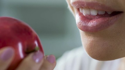 Woman biting red juicy apple by healthy teeth, source of vitamins and calcium