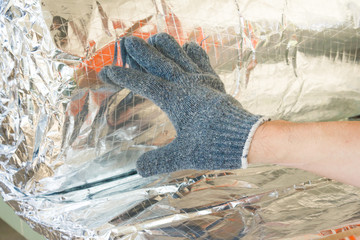 Man hand working insulation aluminum foil encapsulate.