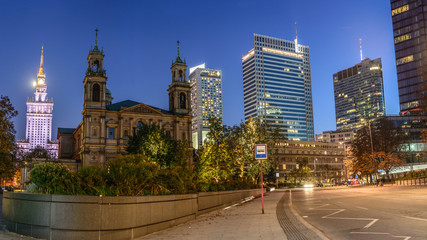 All Saints' Church at Grzybowski Square with skyscrapers in the downtown of Warsaw, Poland during night - 190391822