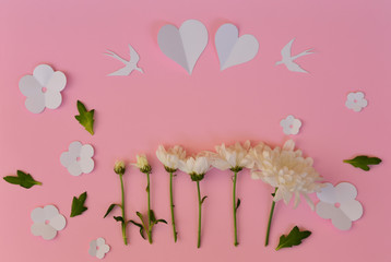 White paper hearts, birds and flowers with real white flowers on pink background