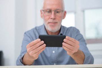 mature handsome  man using smartphone at home