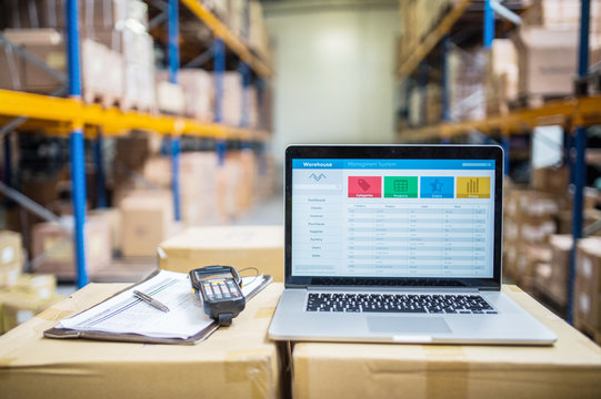Laptop and barcode scanner on boxes in a warehouse.