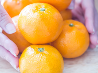 Closeup of oranges on wooden table with woman 's hand.