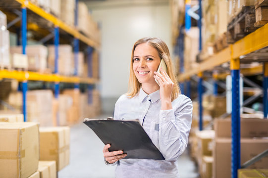 Woman warehouse worker or supervisor with smartphone.