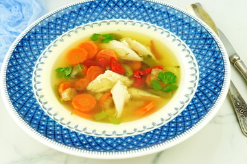 Homemade chicken soup with vegetables in a plate. top view