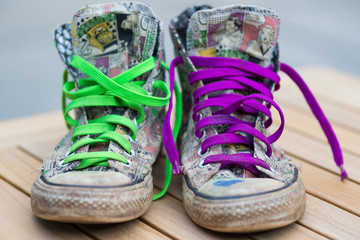 Old and used pair of sneakers. Very colorful with green and pink shoelaces.