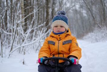 Fototapeta na wymiar cute European boy riding on sled in the woods
