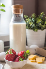 Bottle of milk and a plate of fresh strawberries for breakfast