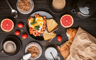 English breakfast. sausage, fried eggs and beans in tomato. coffee and bread nearby. chia with yogur and granola