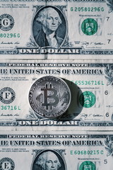 Silver bitcoin coin lying on United States dollars, cryptocurrency concept