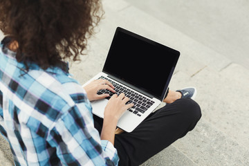 Happy young woman using laptop outdoors