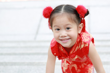Smiling little asian girl in cheongsam on traditional chinese new year festival.