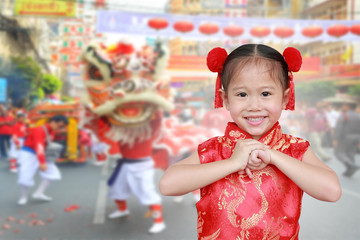 Little chinese girl in traditional Chinese cheongsam blessing for you in chinese new year festival.