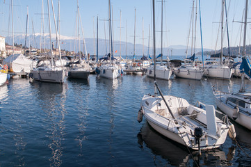 Fototapeta premium Il porto con le barche sul lago di Garda sullo sfondo della montagna innevata