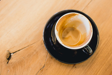 Finished drink of Latte coffee in black cup on wood table background